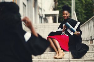 woman-wearing-black-graduation-coat-sits-on-stairs
